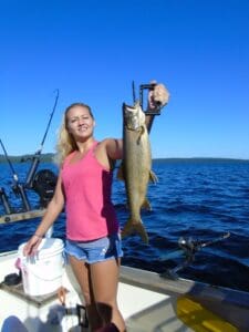 A young lady holding up her catch of a Moosehead Laker on a Moosehead Lake Fishing Charter in Maine