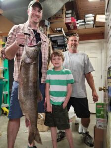 Guests holding trophy lake trout caught on a fishing charter in Moosehead Lake Maine
