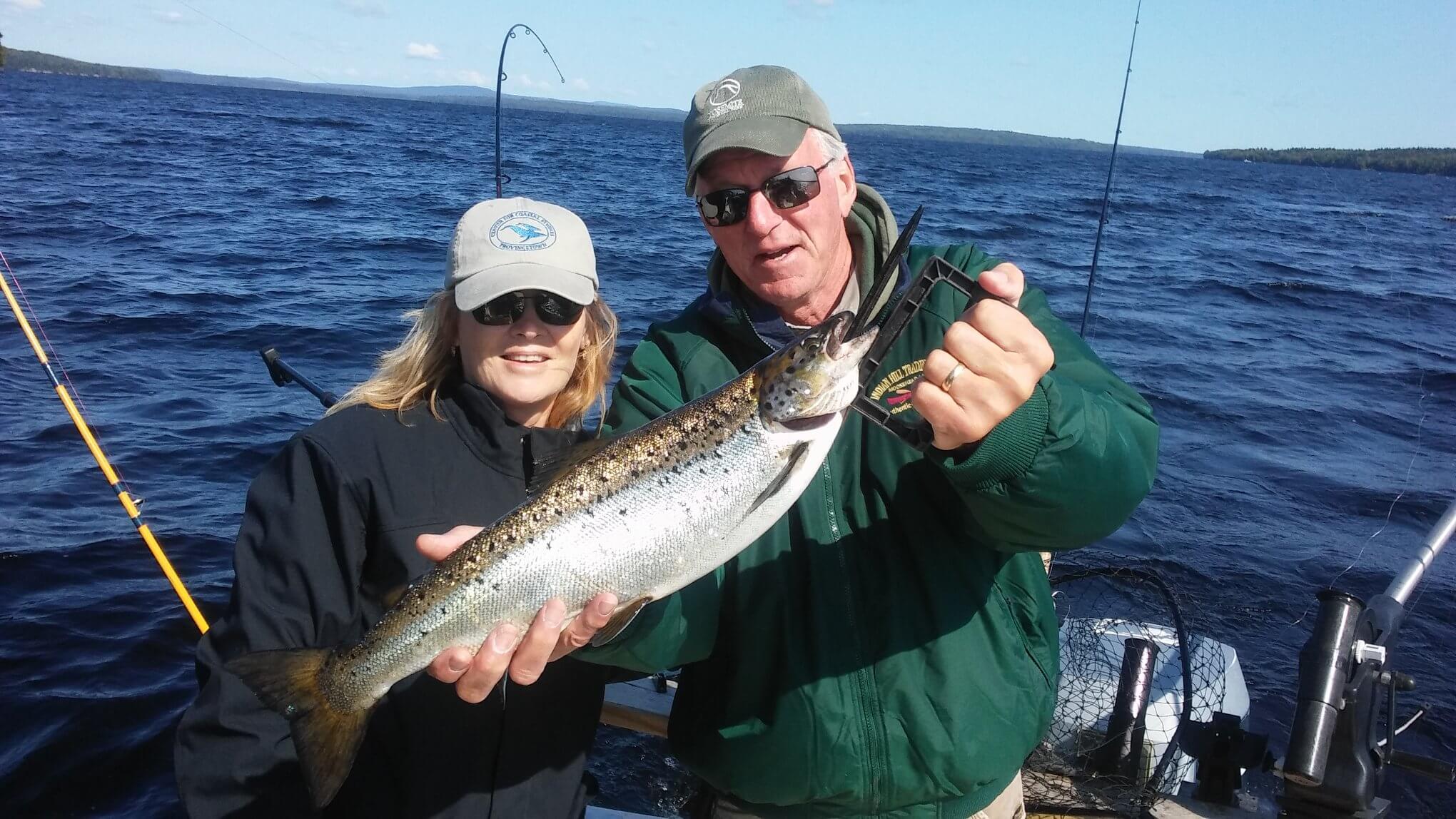 Guests holding salmon caught on a fishing charter in Moosehead Lake Maine