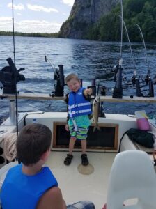 Young angler holding a fish on a fishing charter in Moosehead Lake Maine